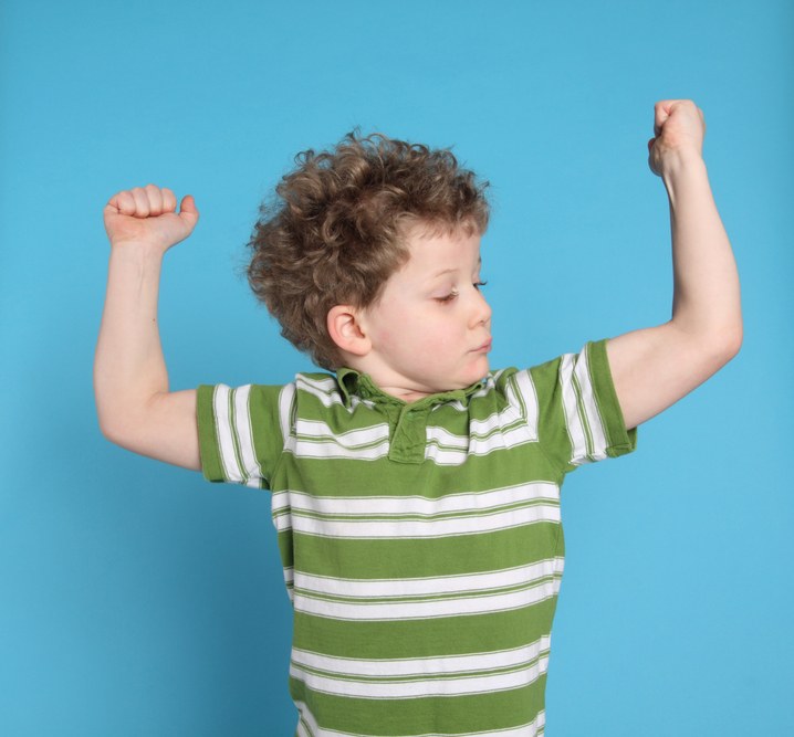 A small boy flexing his muscles